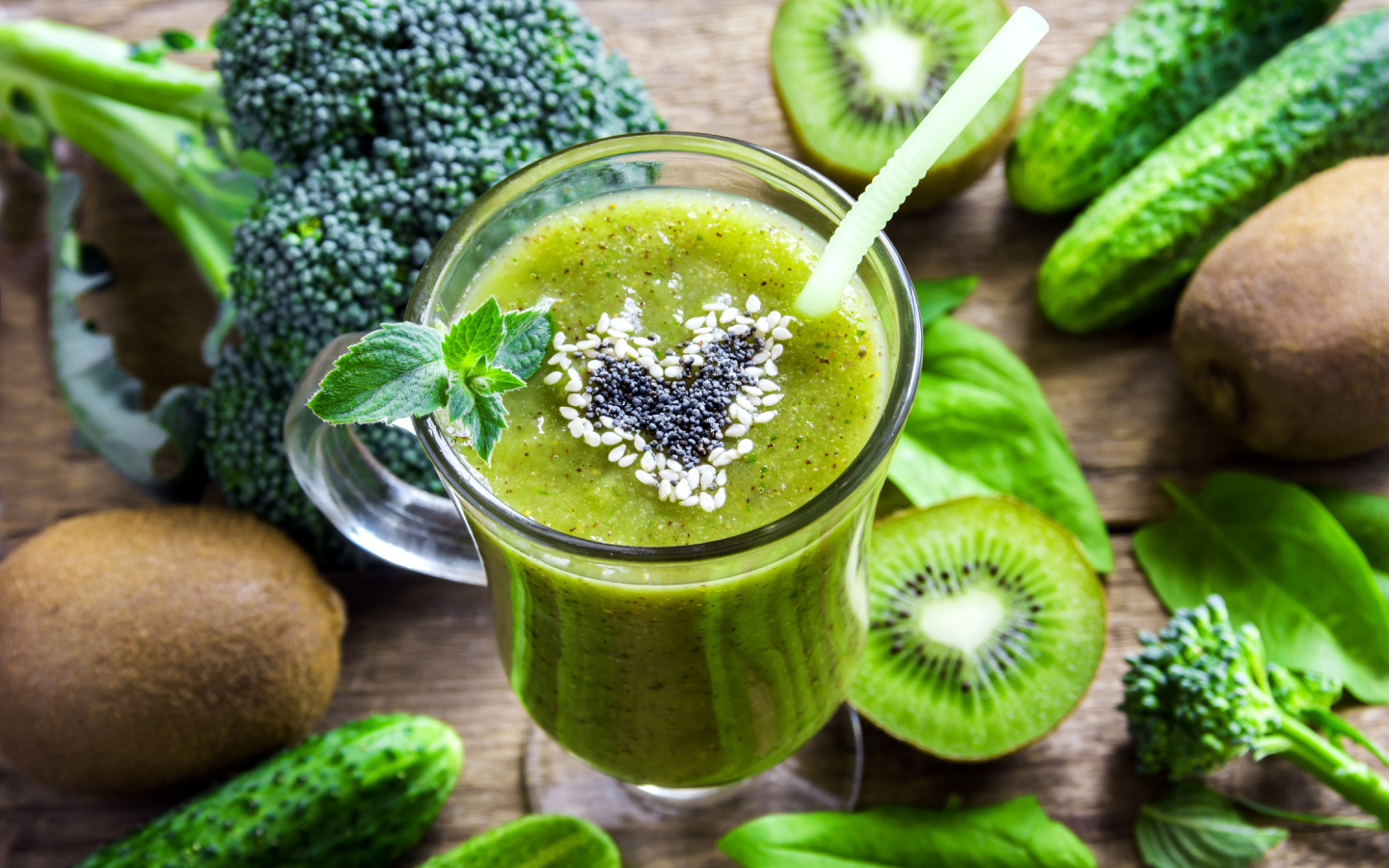 Стакан зеленого смузи на столе с киви, огурцами и брокколи