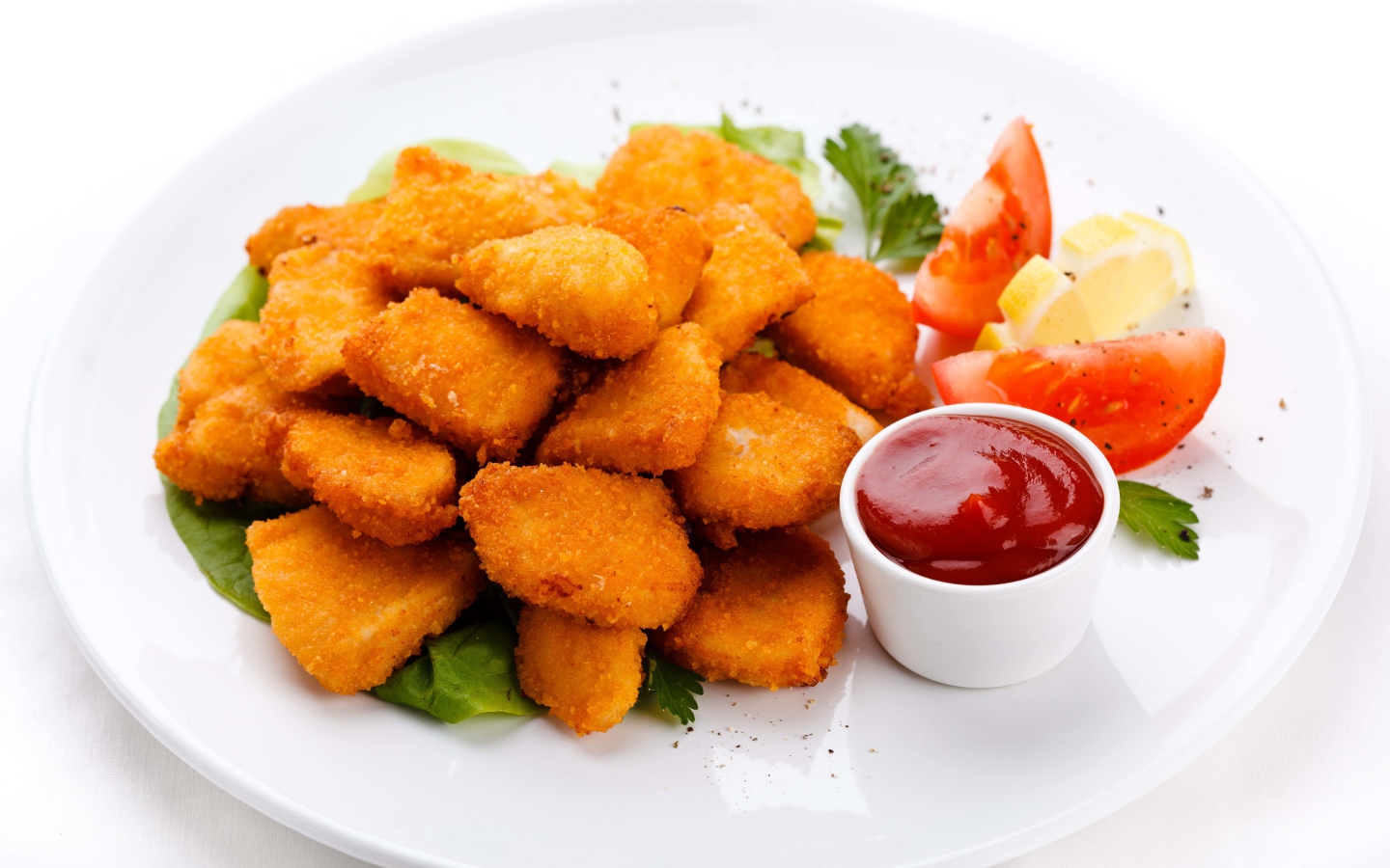 Куриные наггетсы с соусом и помидорами на белой тарелке 