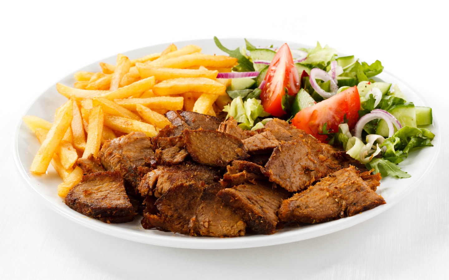 Slices of meat on a plate with french fries and salad