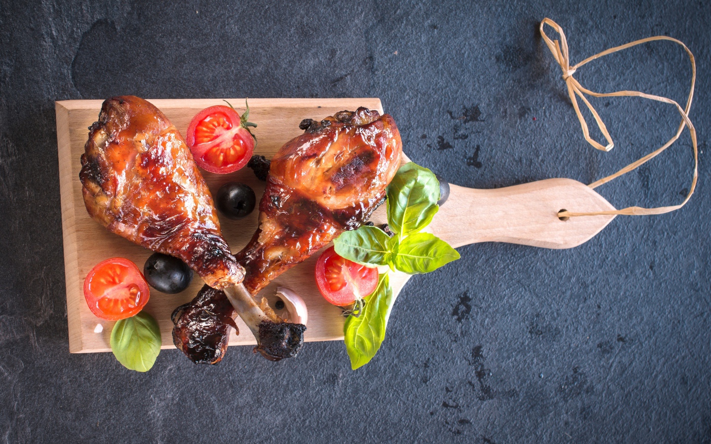 Две зажаренных куриных ножки с овощами на разделочной доске