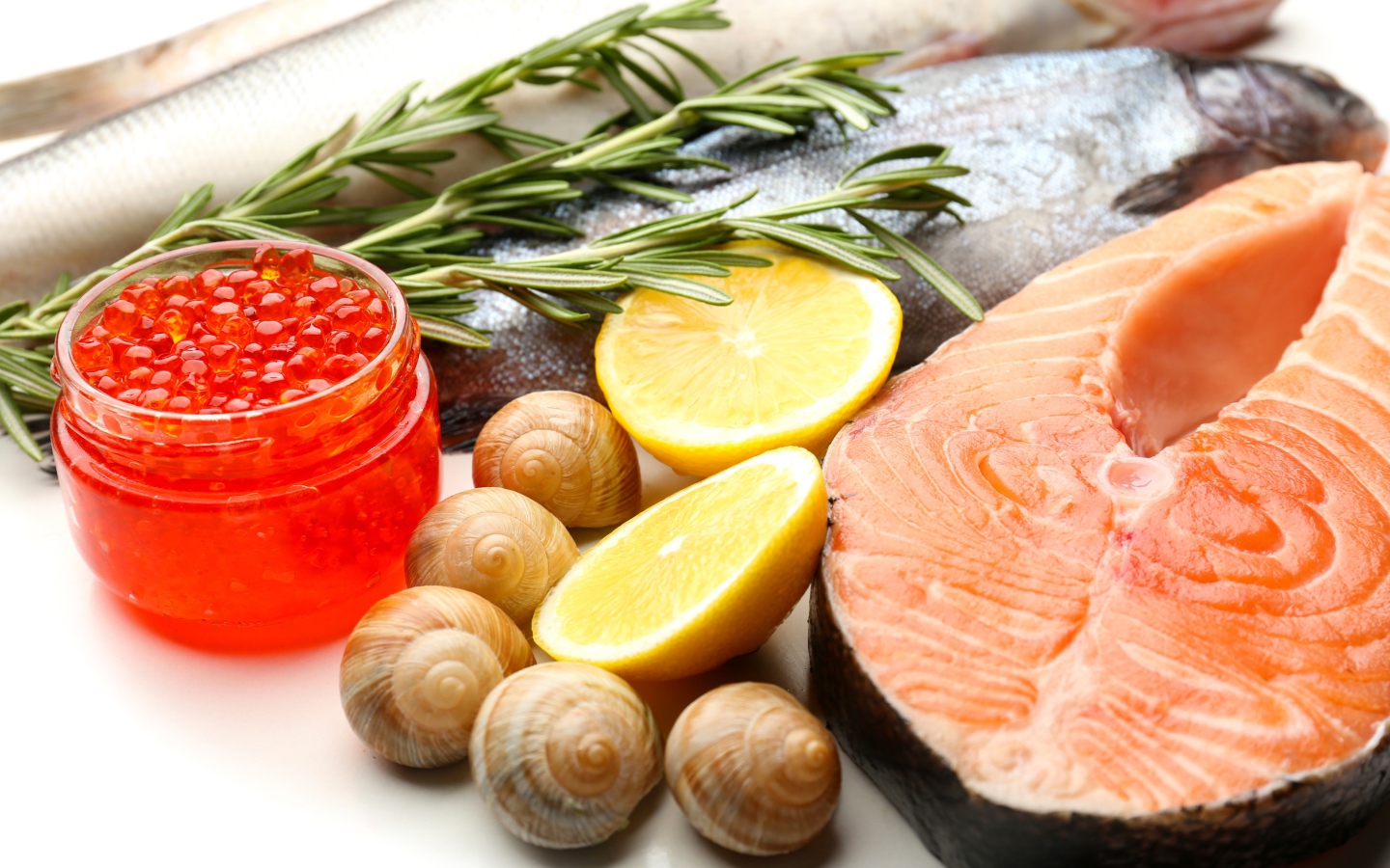 Красная рыба с улитками и красной икрой на столе с лимоном и базиликом