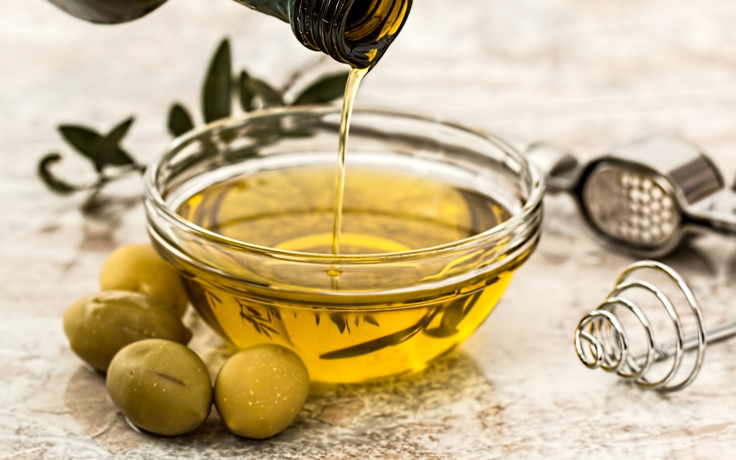 Оливковое масло в стеклянной посуде на столе с зелеными оливками