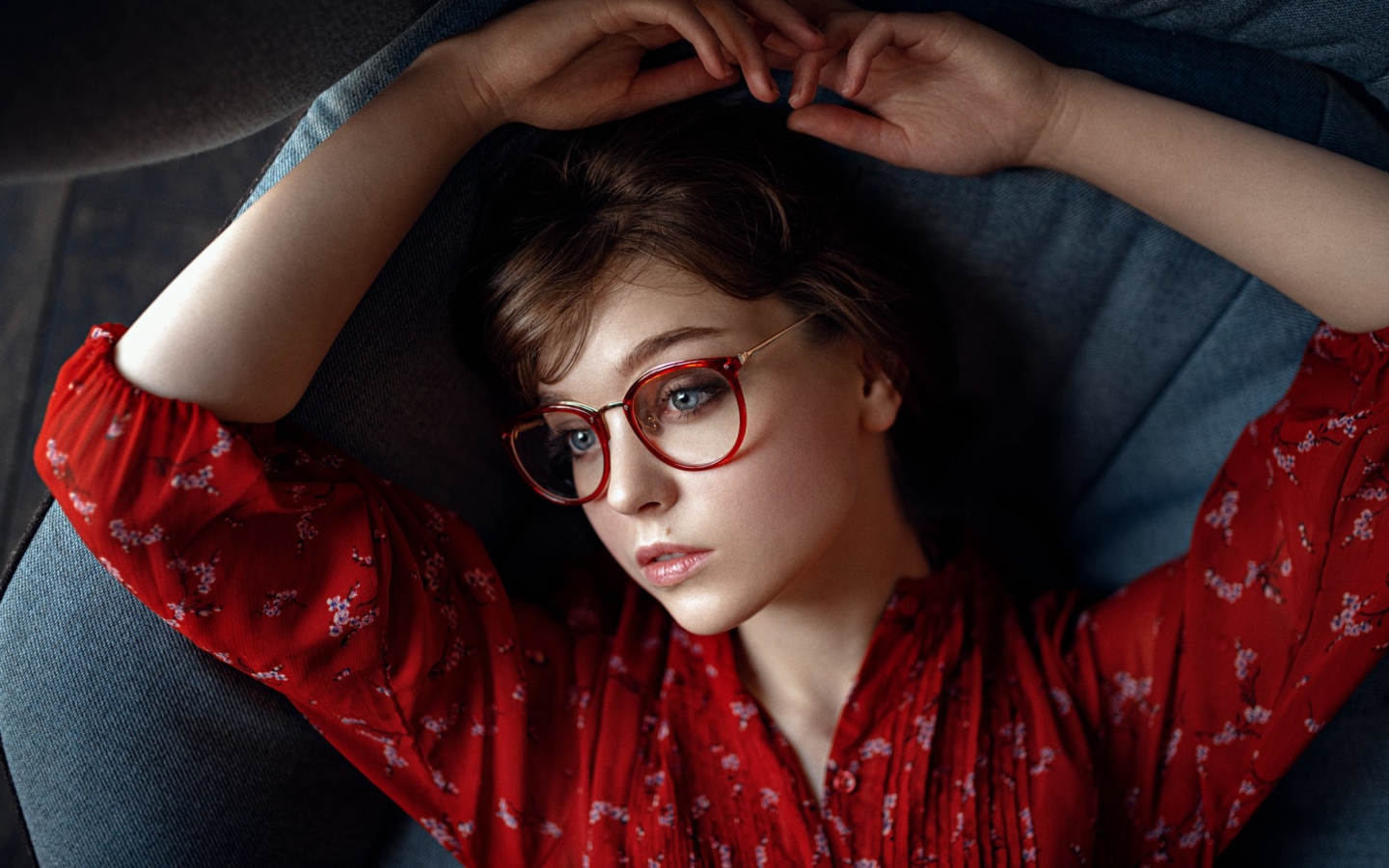 Молодая девушка в очках лежит на диване 