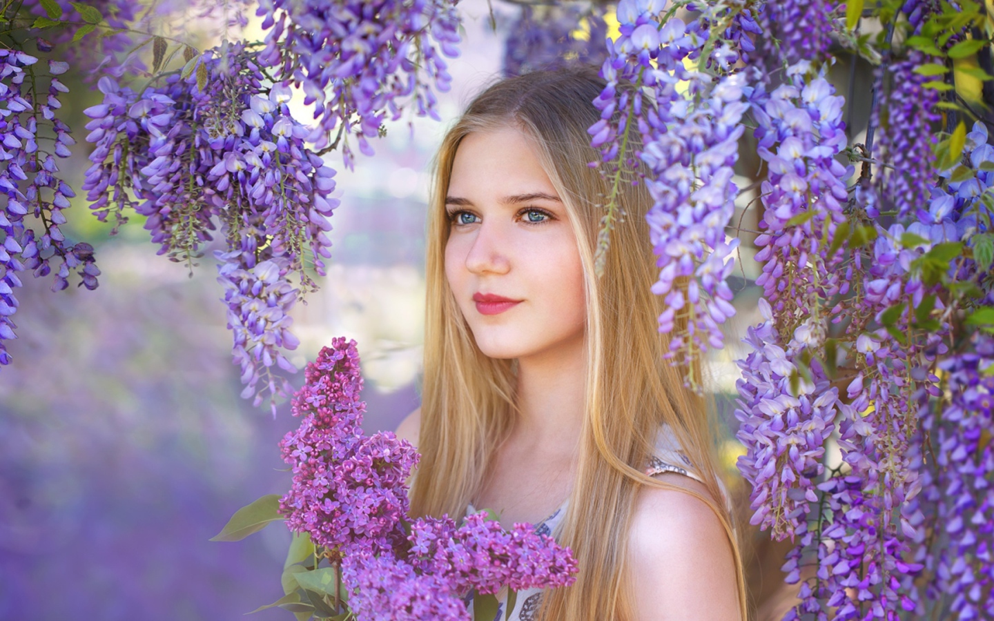 Красивая блондинка с букетом сирени на фоне цветов глицинии
