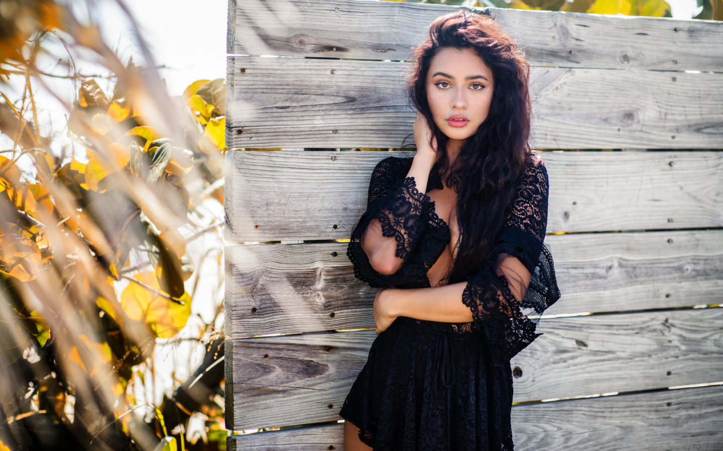 Красивая девушка в черном платье у стены 