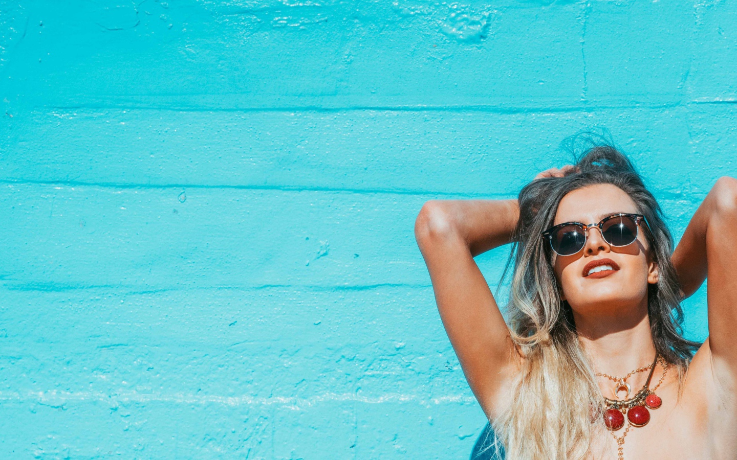 Красивая девушка в солнечных очках загорает на солнце летом