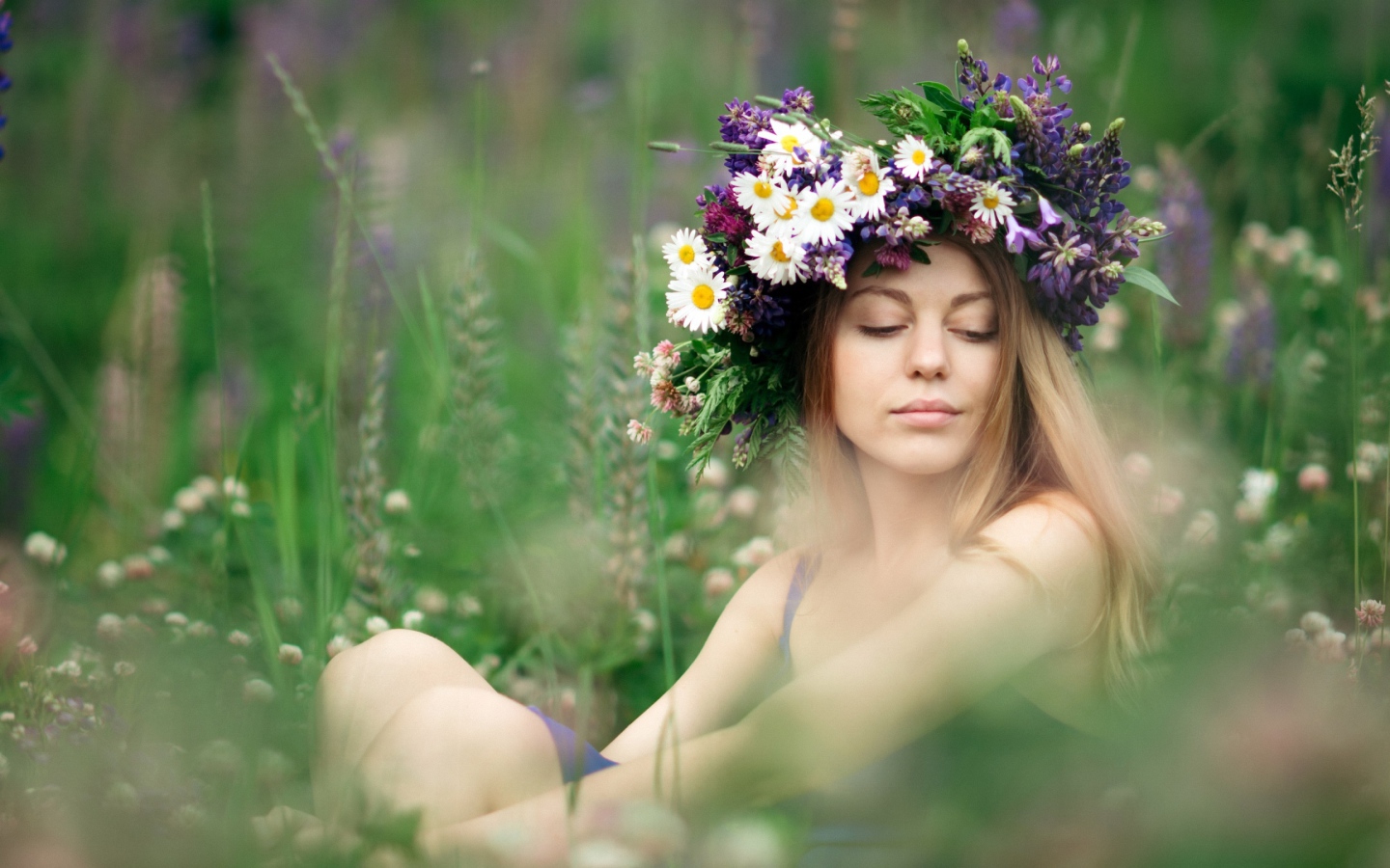 Красивая девушка с венком из полевых цветов на голове летом 
