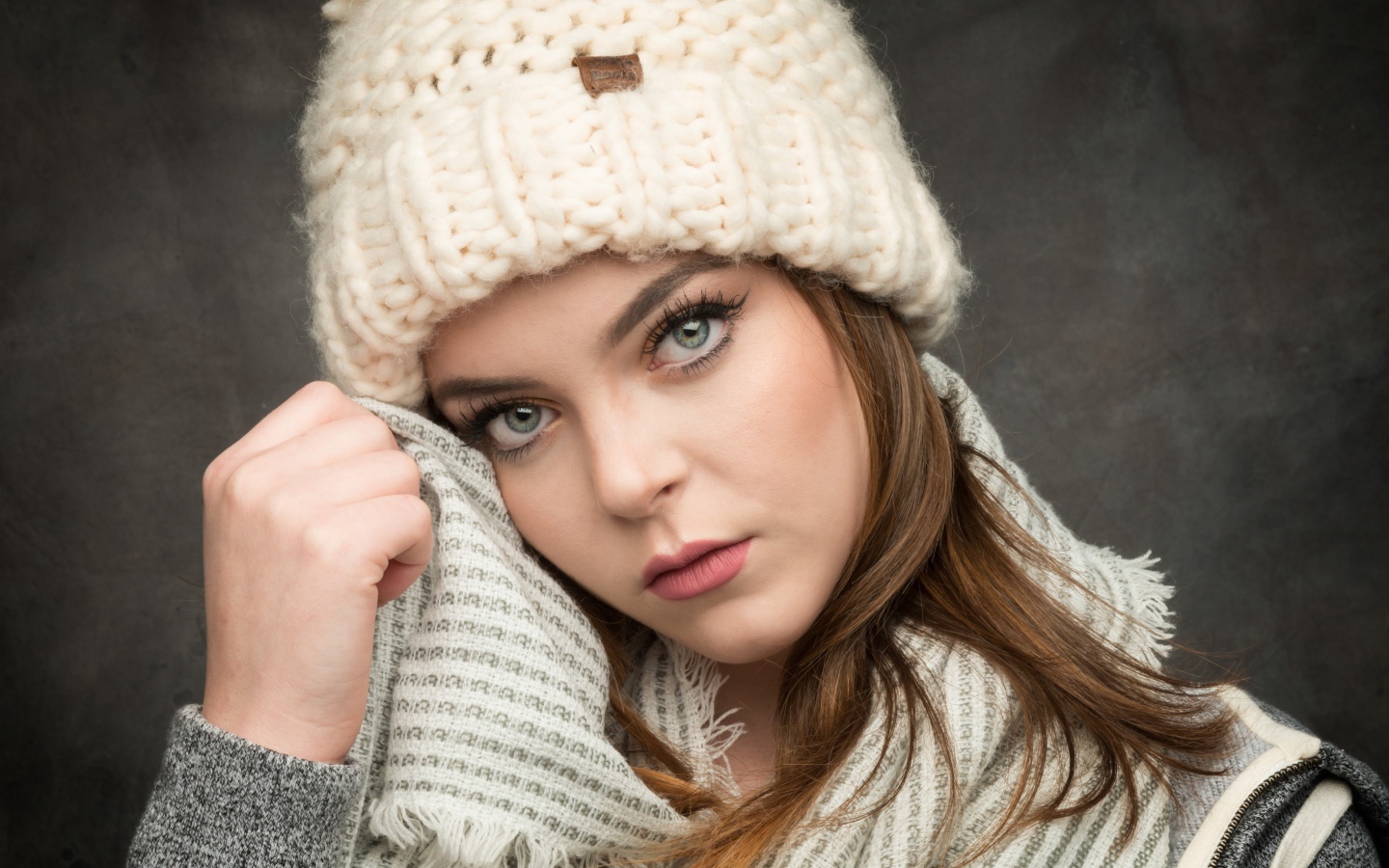 Красивая зеленоглазая девушка в белой вязаной шапке с шарфом
