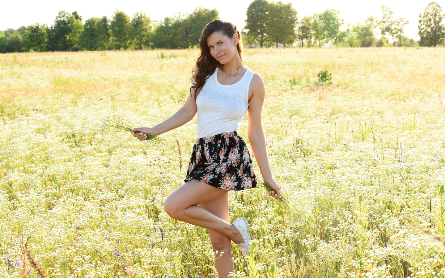 Красивая молодая девушка на поле с белыми ромашками