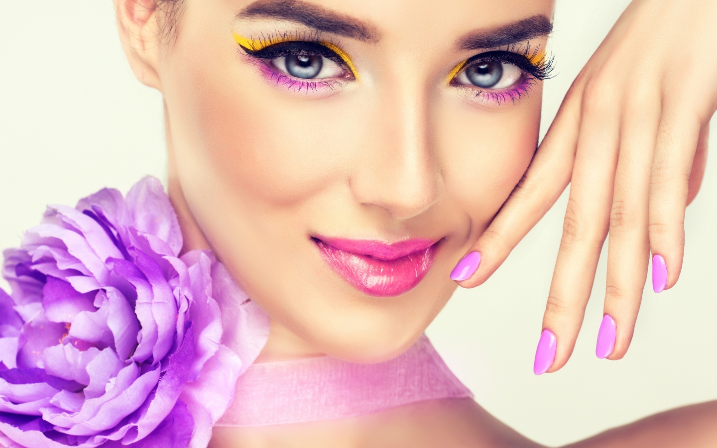 Красивая молодая девушка с ярким макияжем и сиреневым цветком на шее