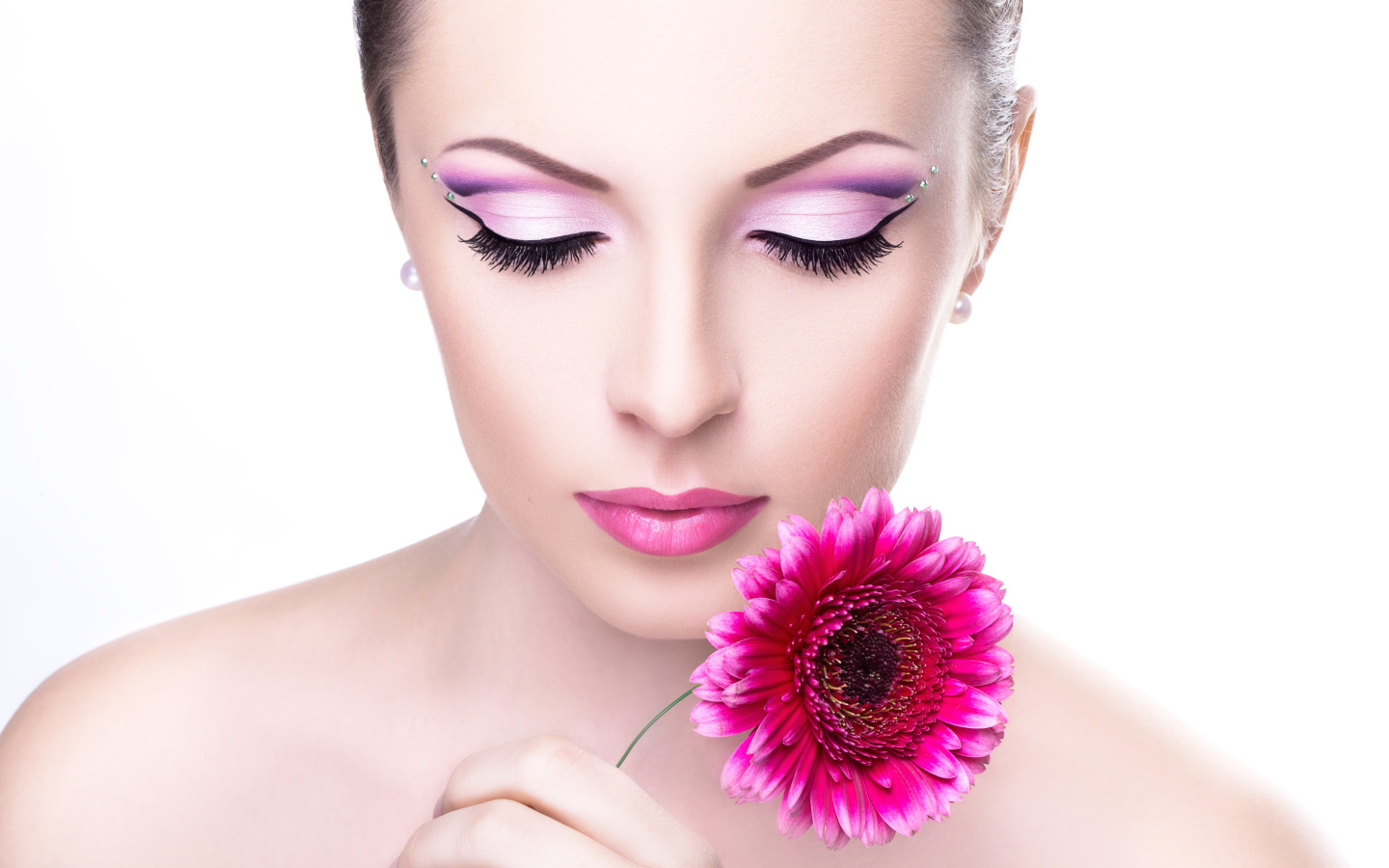 Model girl with a gentle make-up with a pink gerbera flower in her hand