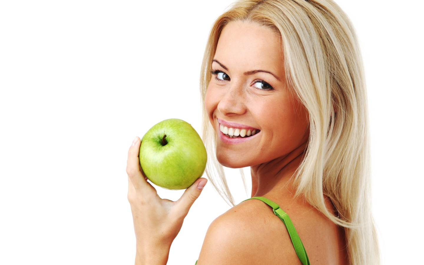 Улыбающаяся девушка блондинка с зеленым яблоком в руке на белом фоне