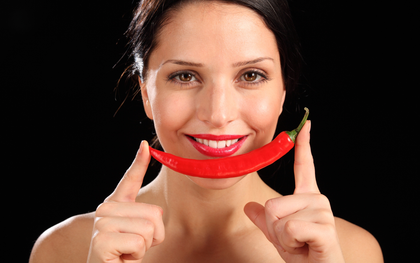 Улыбающаяся девушка с красным перцем на черном фоне