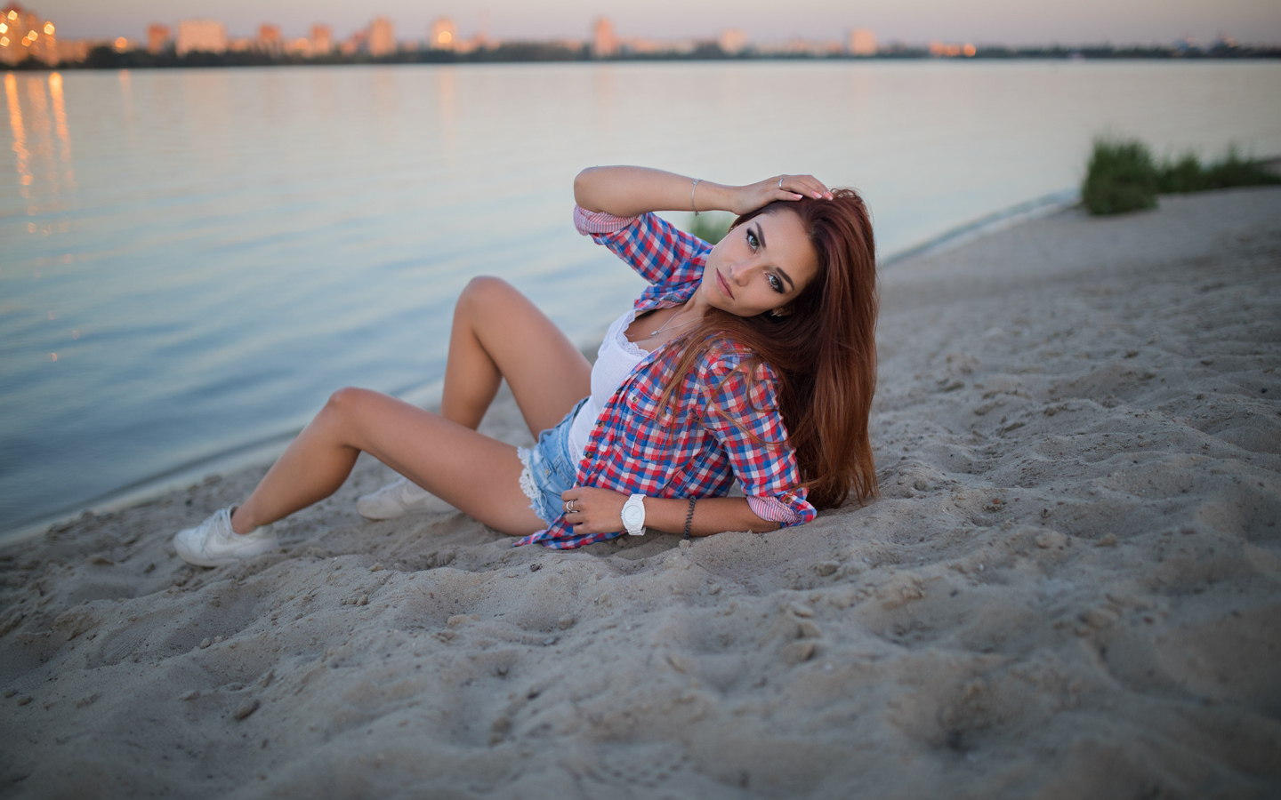 Молодая девушка лежит на песке у реки