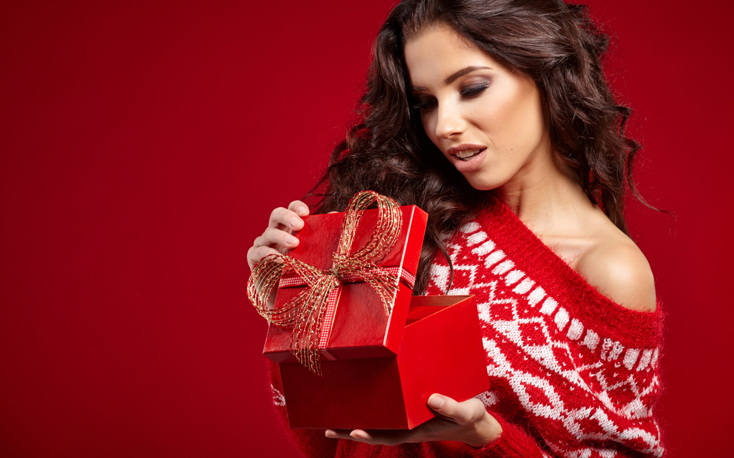 Красивая брюнетка с подарком на красном фоне
