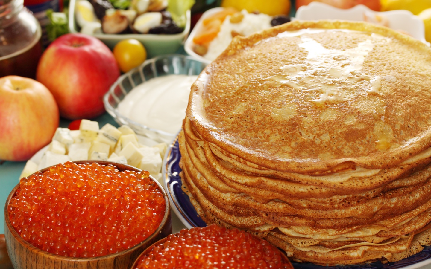 Румяные тонкие блины на столе с красной икрой на Масленицу