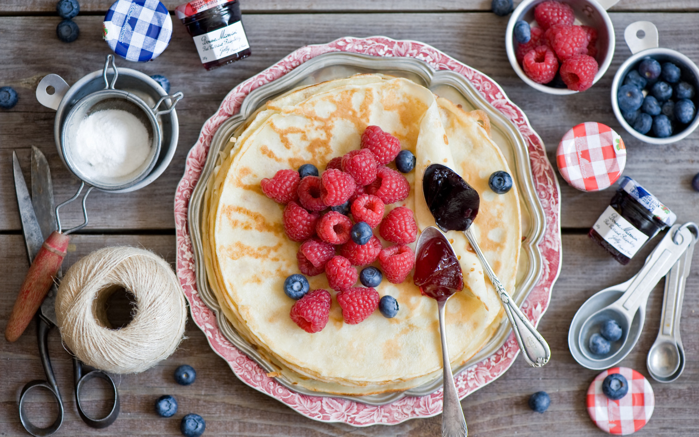Тонкие блины с малиной и черникой на столе вид сверху