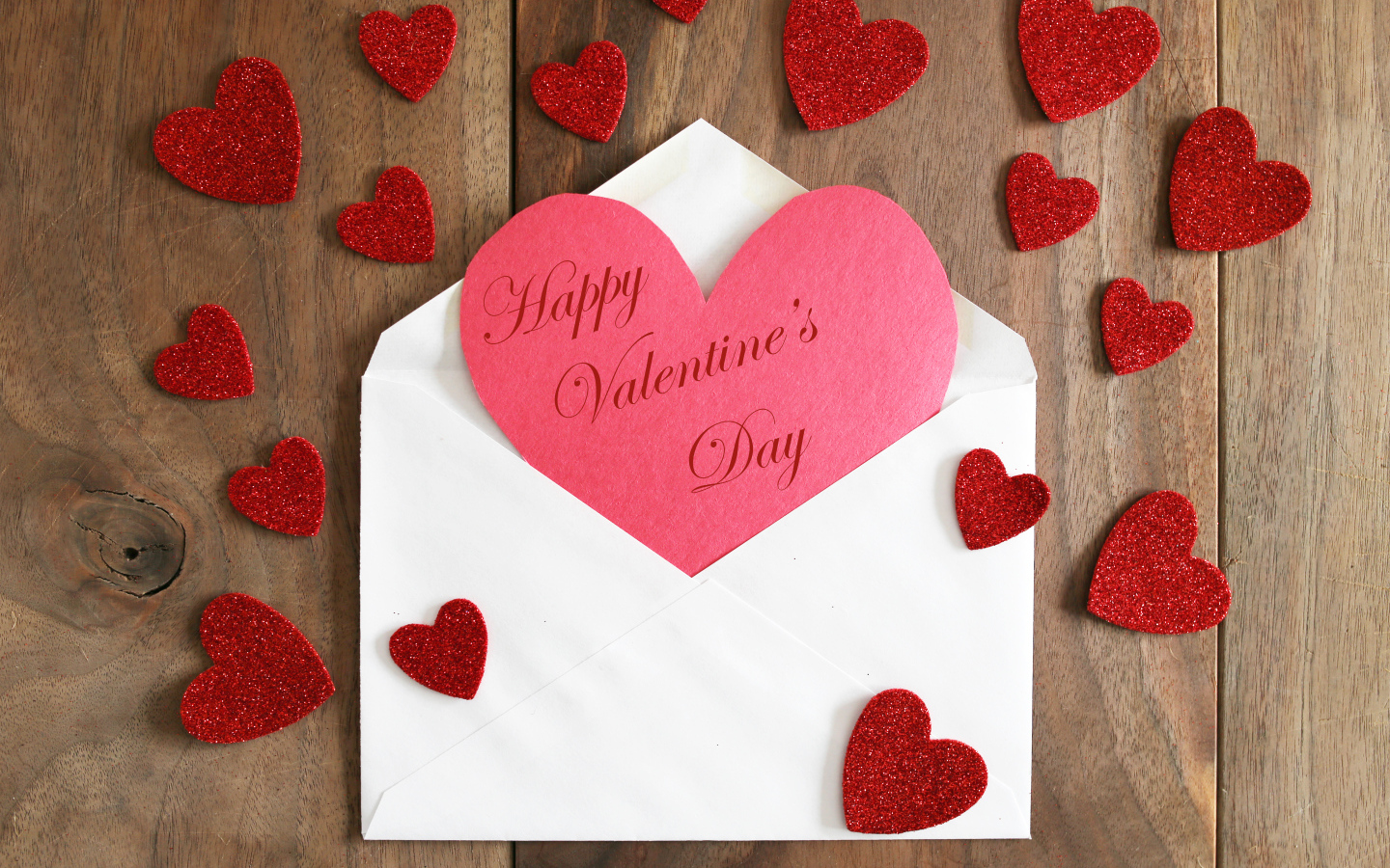 Белый конверт с валентинкой на деревянном столе с красными сердечками на 14 февраля