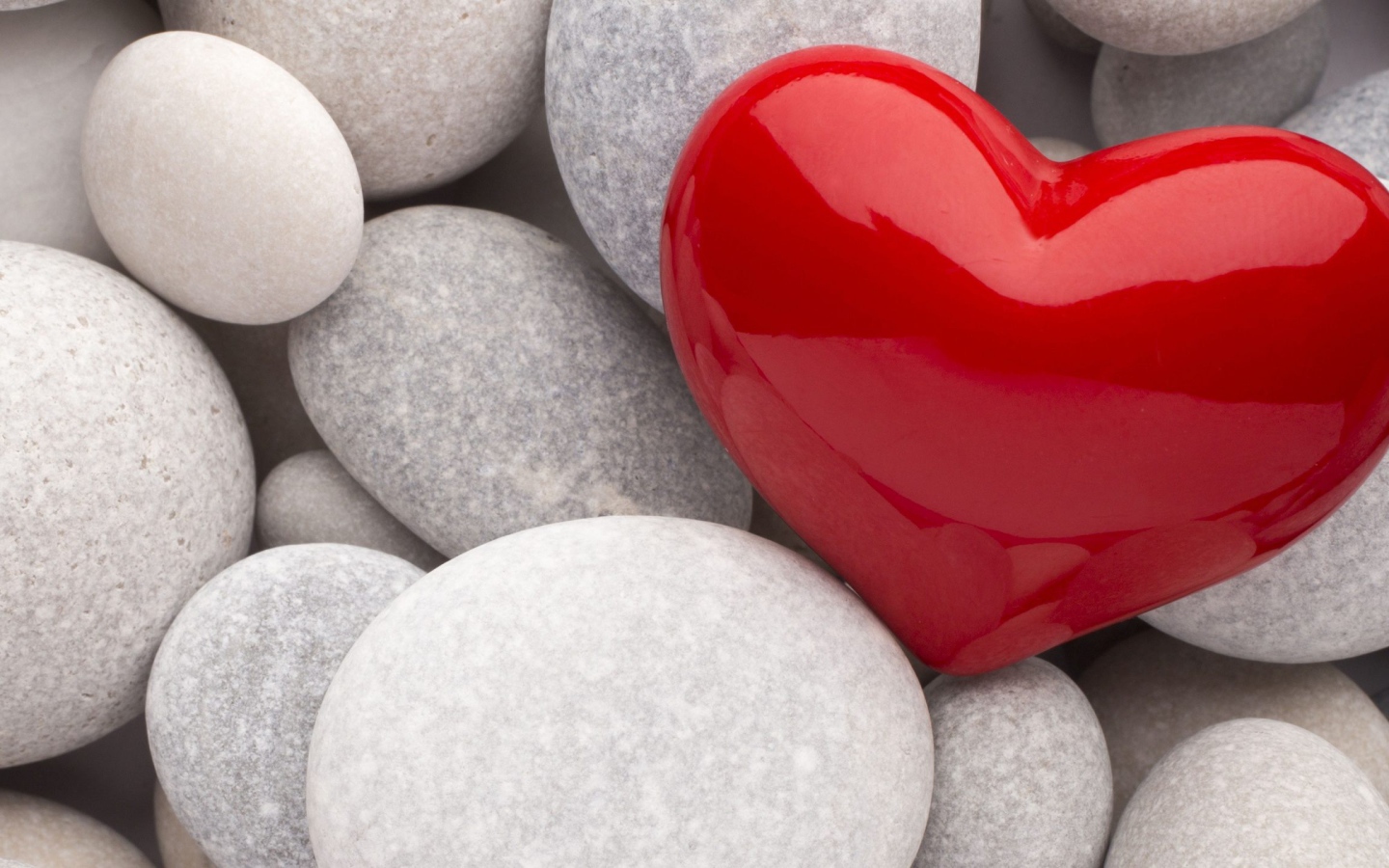 Красное сердце лежит на серых камнях 