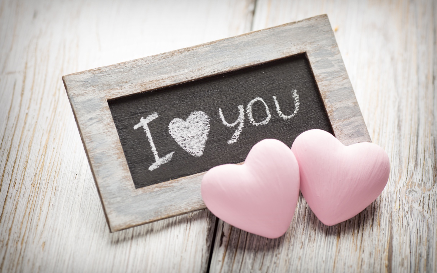 Два розовых сердца на столе с деревянной рамкой