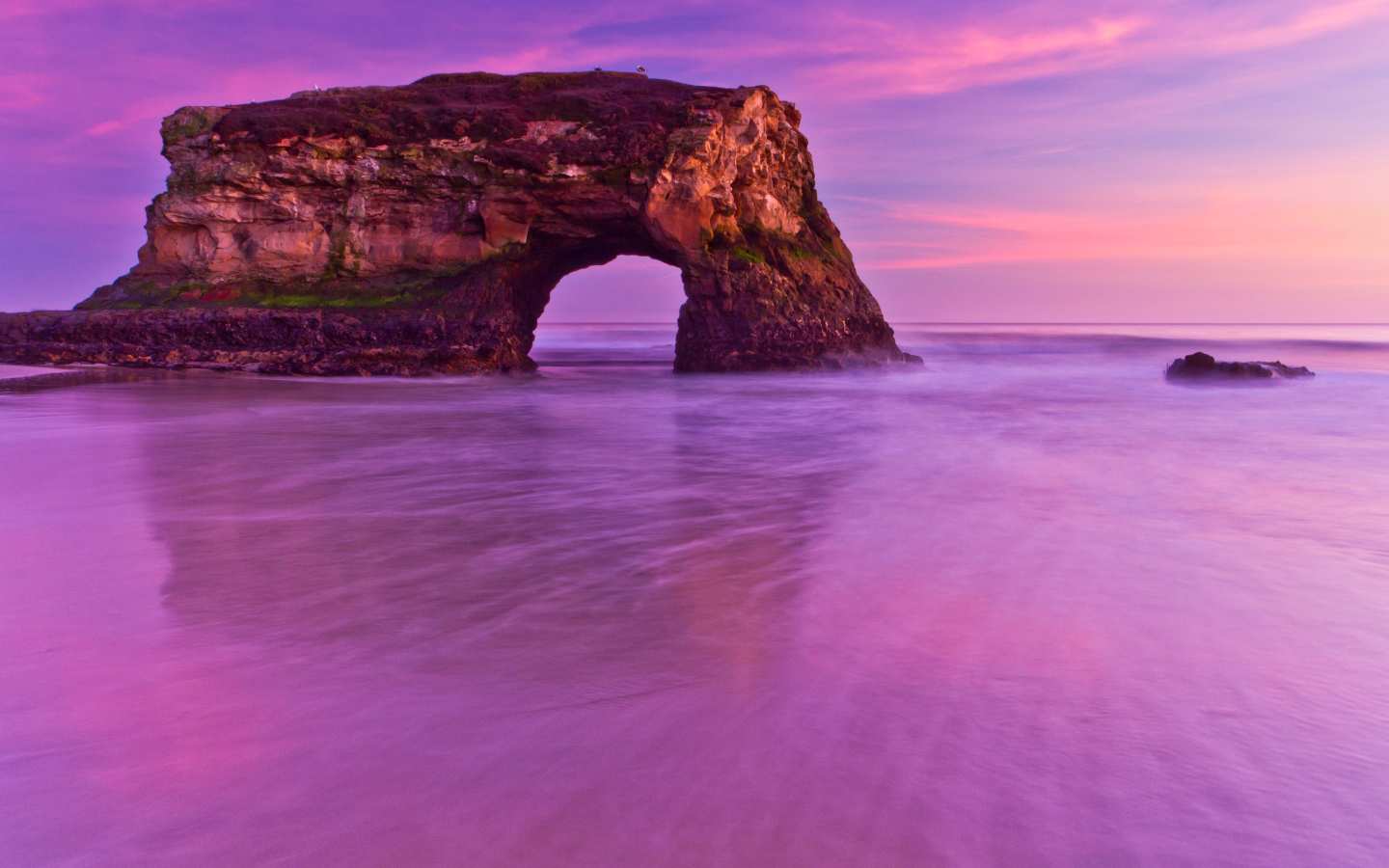 Гора с аркой в океане на фоне красивого неба