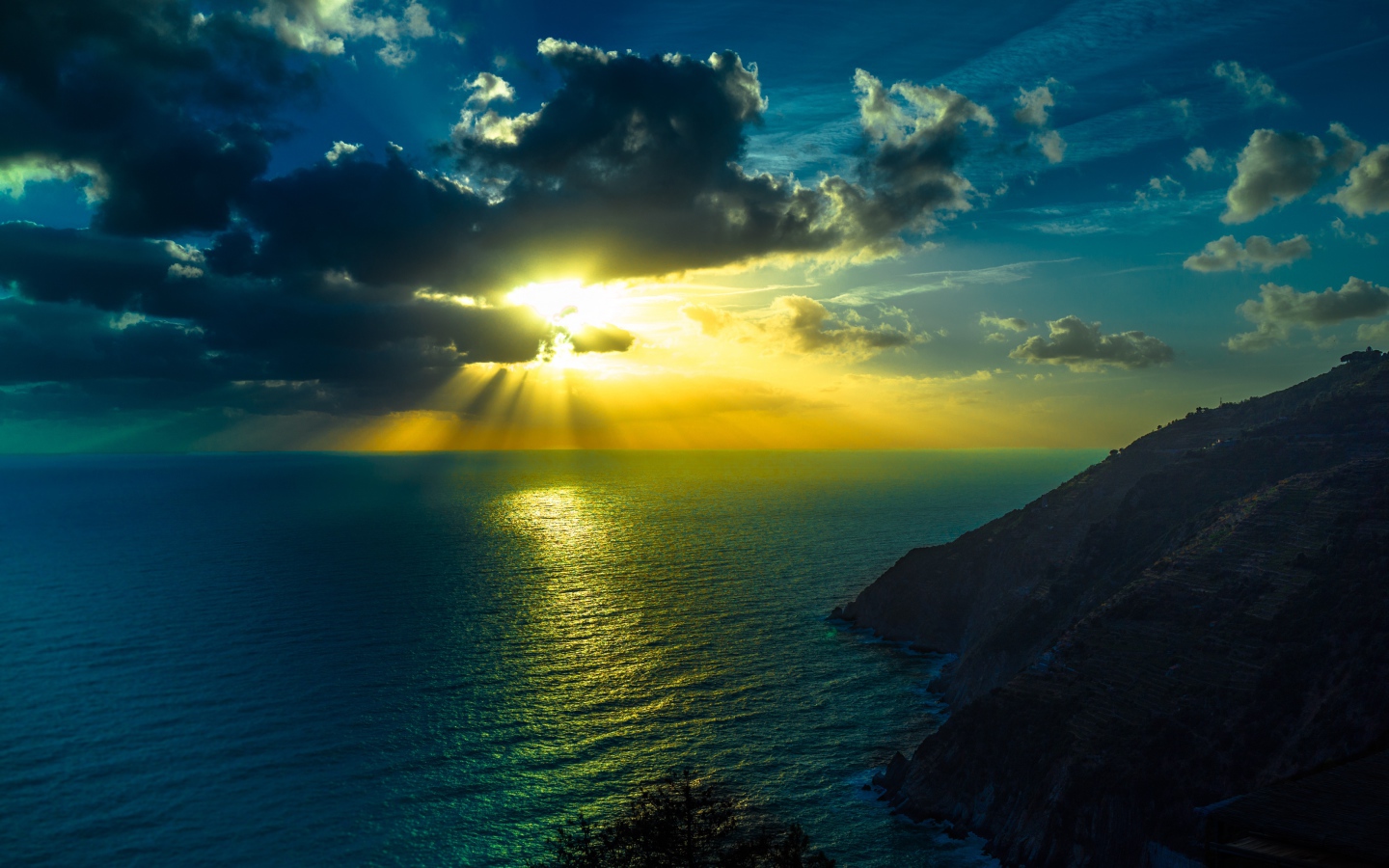 Лучи яркого солнца пробиваются сквозь облака над морем