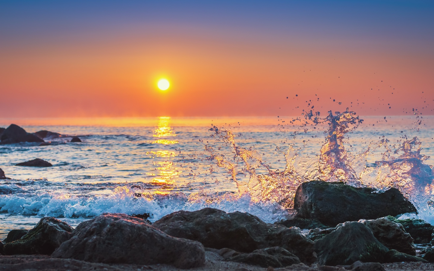 Волны бьются о камни на морском побережье на закате