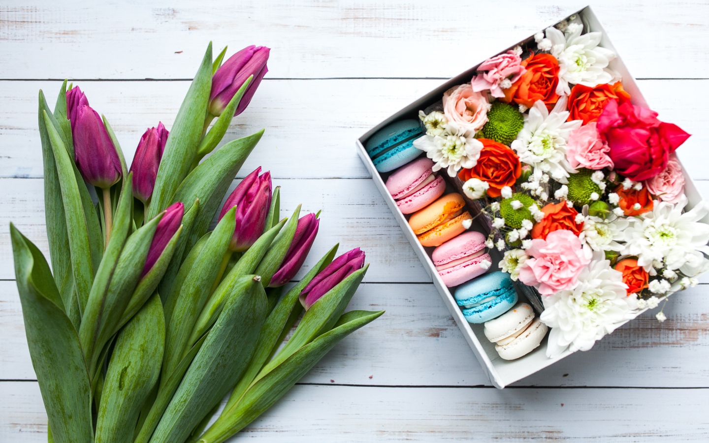 Букет сиреневых тюльпанов на столе с коробкой с макарунами
