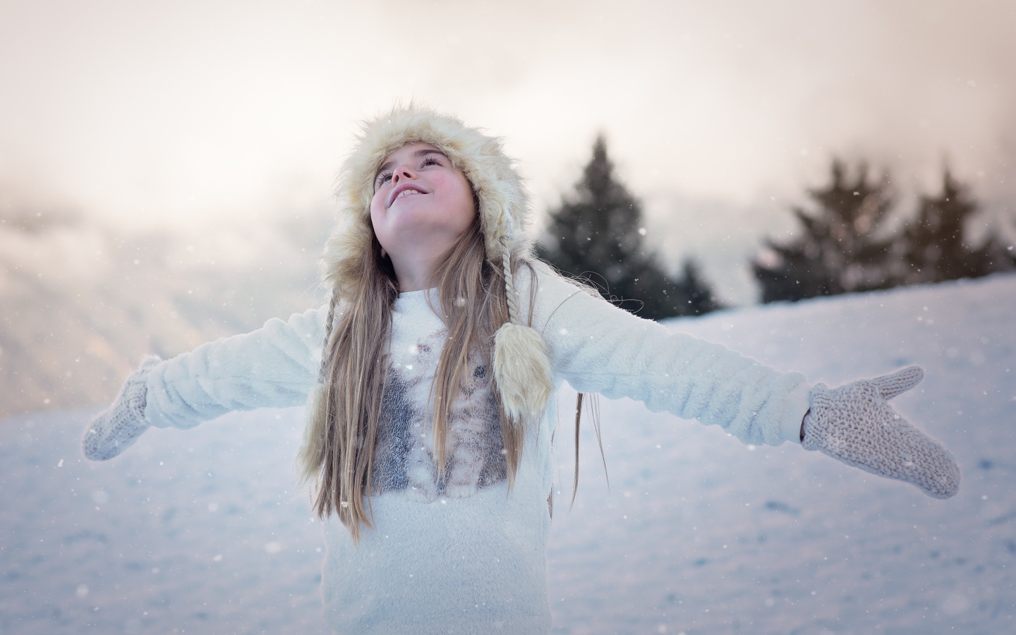 Девочка в белой шапке радуется снегу