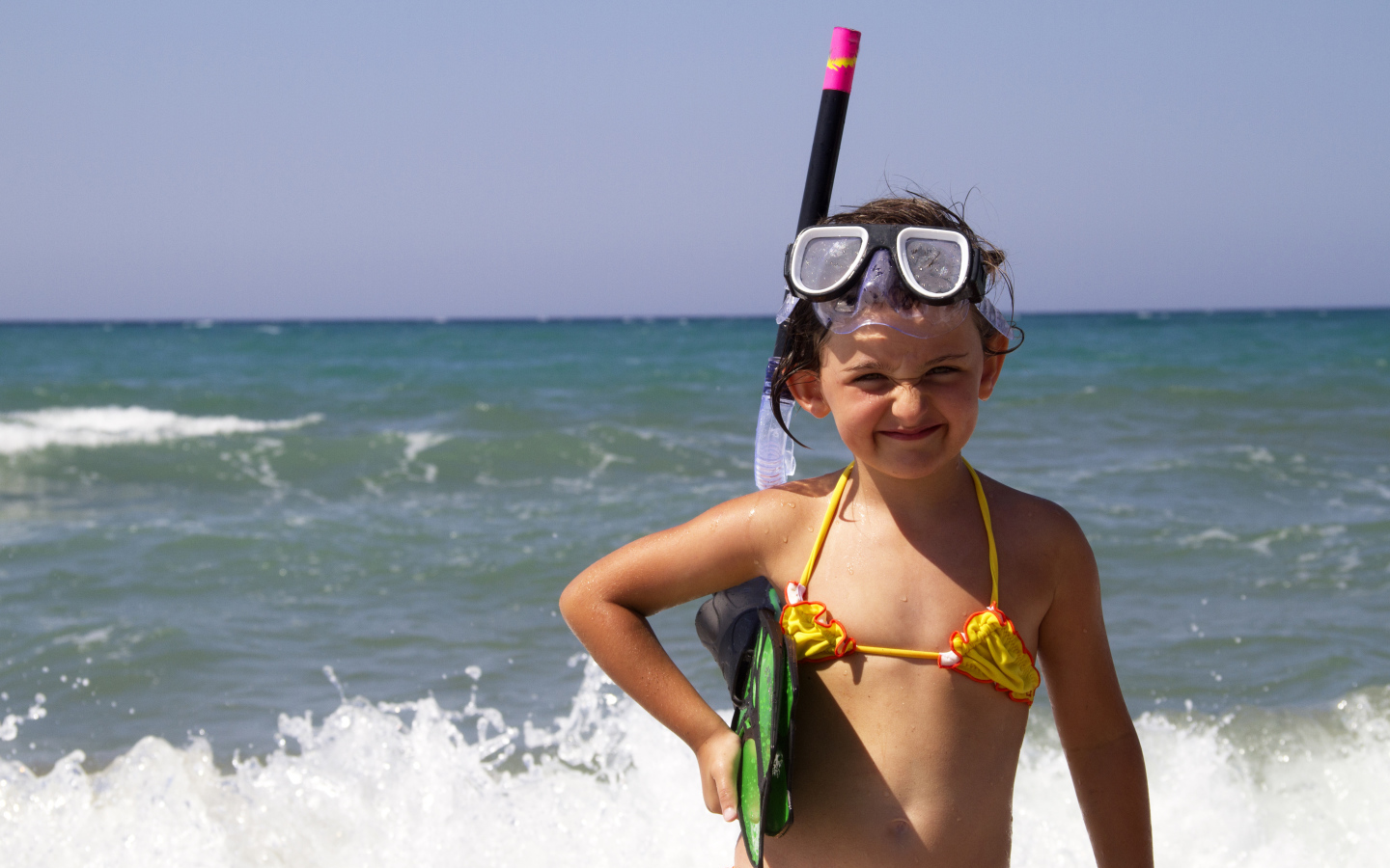 Маленькая девочка в очках и с ластами на море