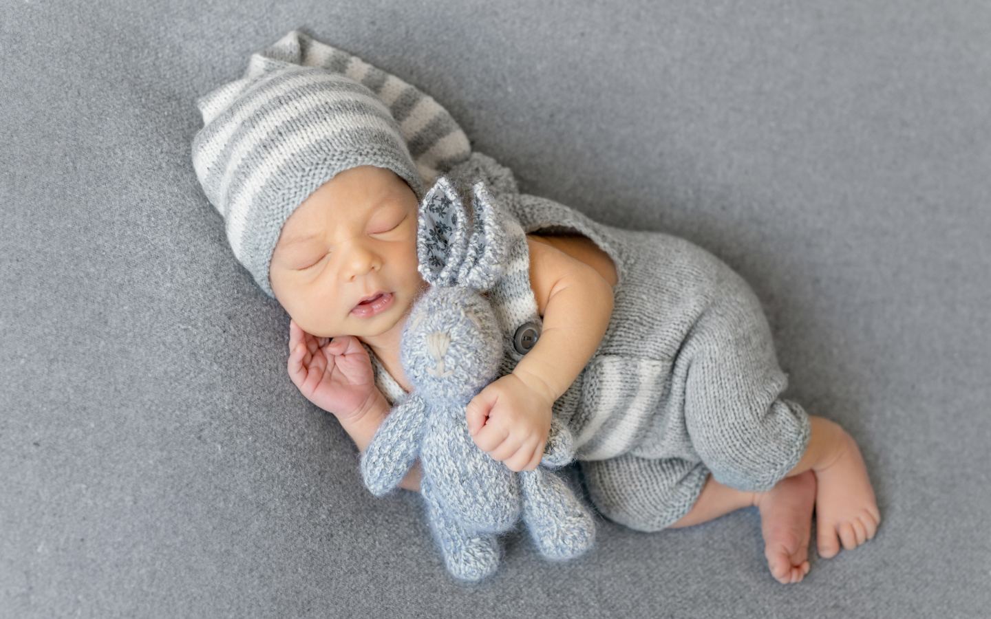 Спящий младенец с серым вязаным зайцем