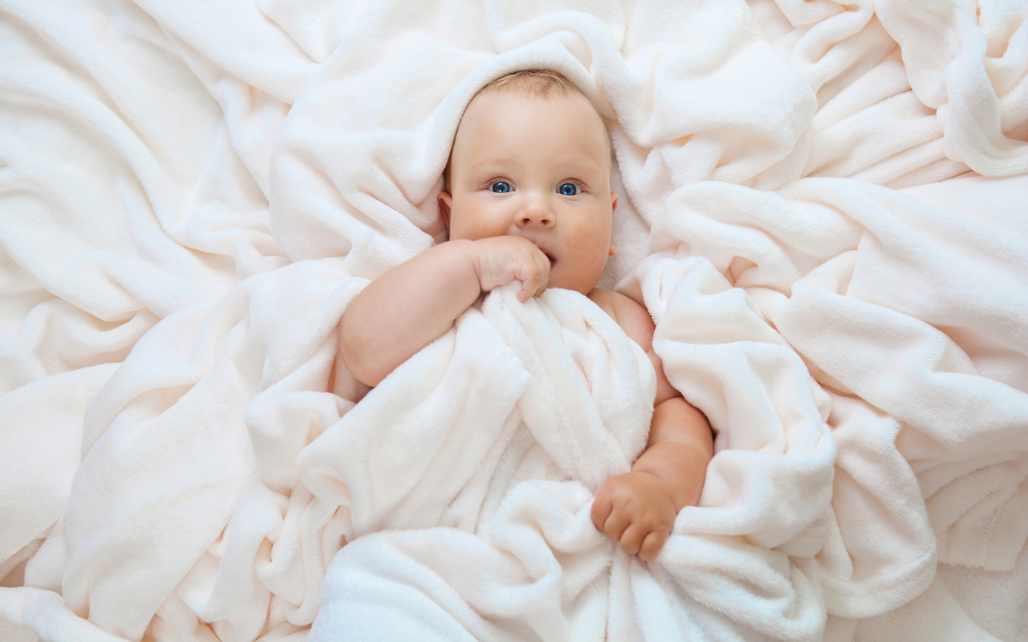 Маленький голубоглазый ребенок в покрывале 