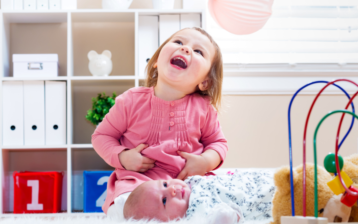 Смеющаяся маленькая девочка с младенцем