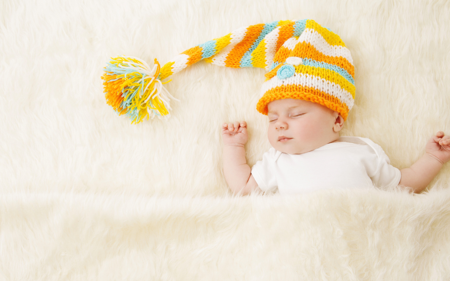 Маленький спящий под меховым покрывалом малыш в вязаной шапке