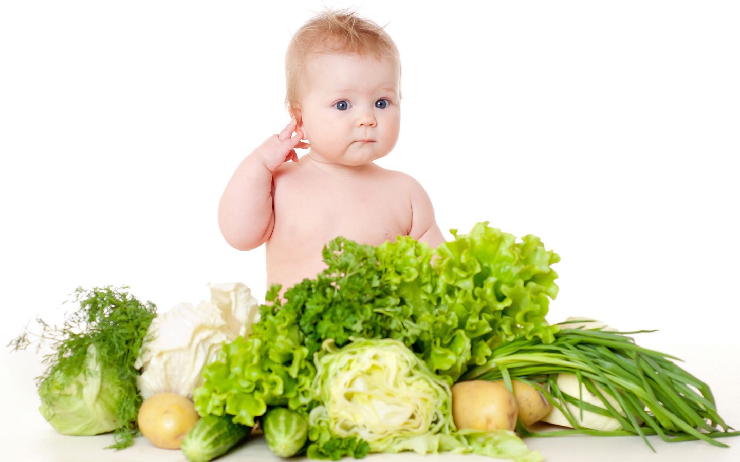 Маленький ребенок с овощами и зеленью на белом фоне