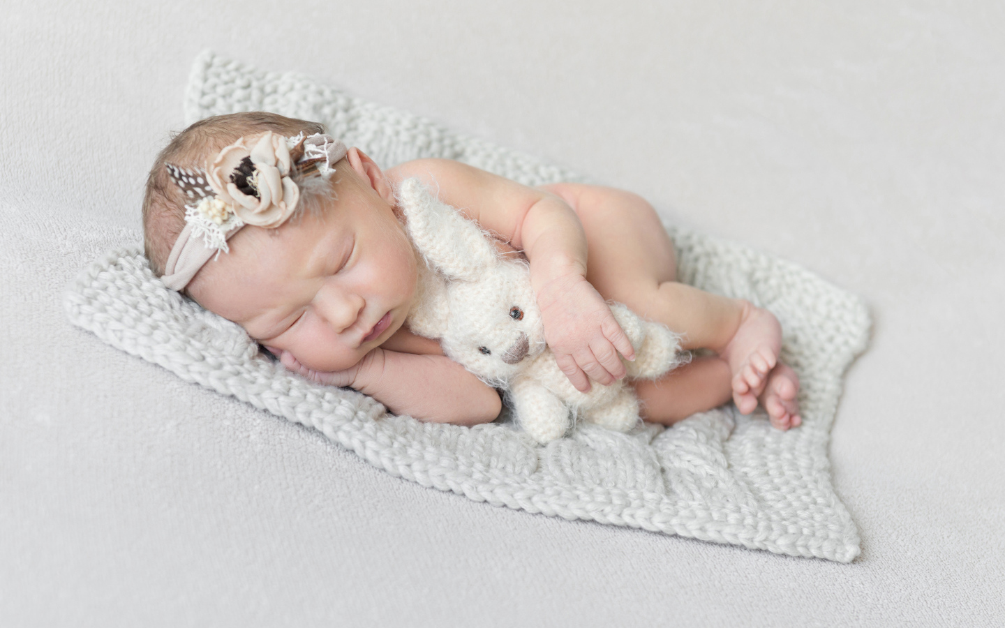 Спящий грудной ребенок с вязаной игрушкой