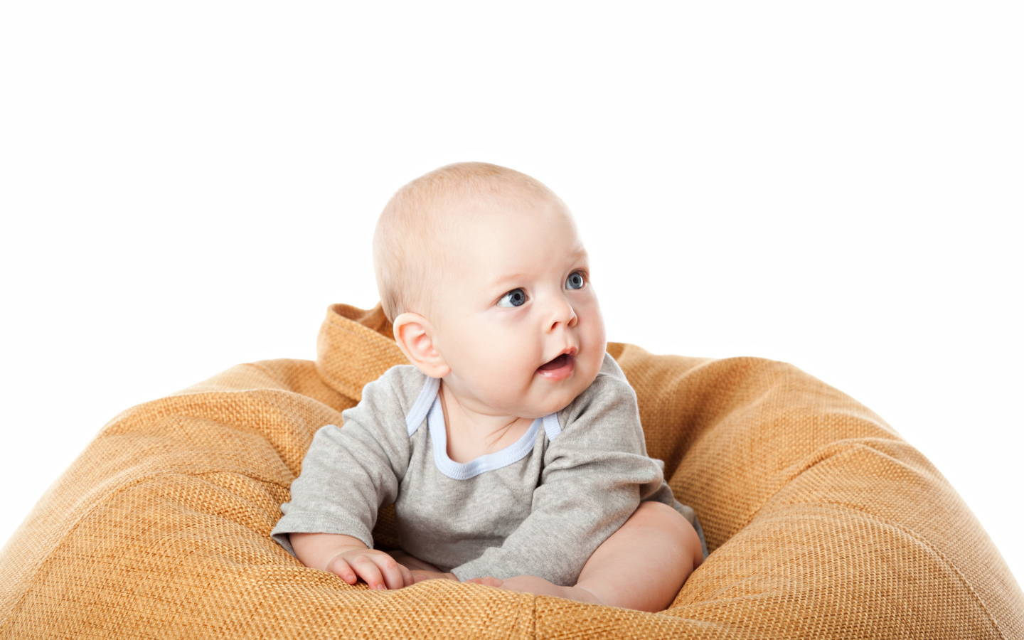 Младенец сидит на подушке на белом фоне