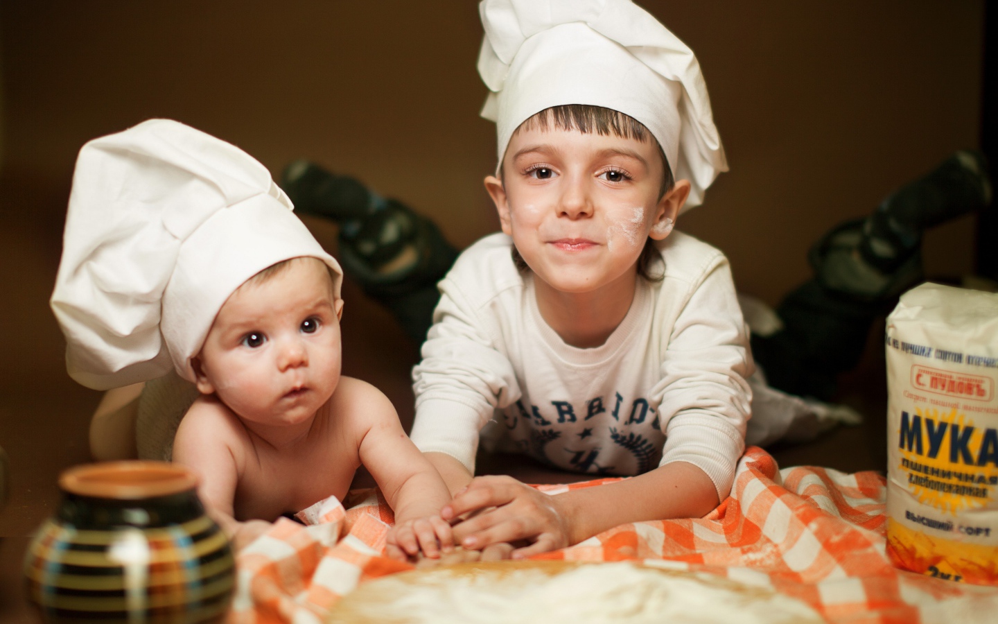 Два маленьких мальчика в шапках повара на кухне