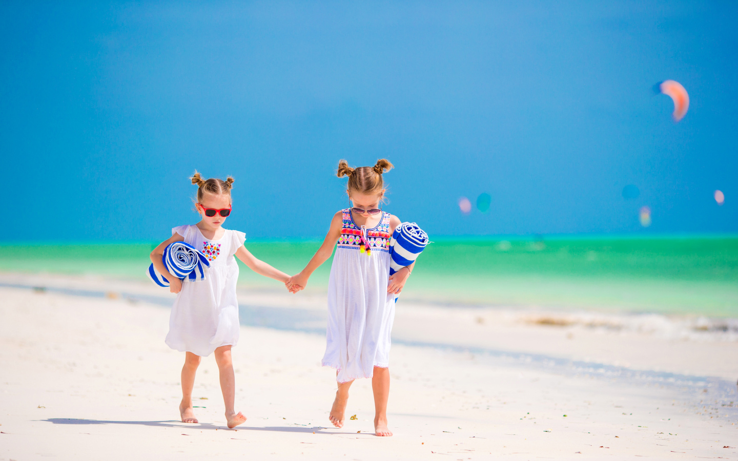 Две маленькие девочки идут по песку