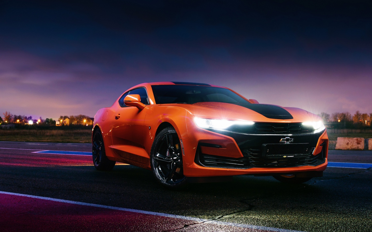 Оранжевый автомобиль Chevrolet Camaro, 2019 года с включенными фарами