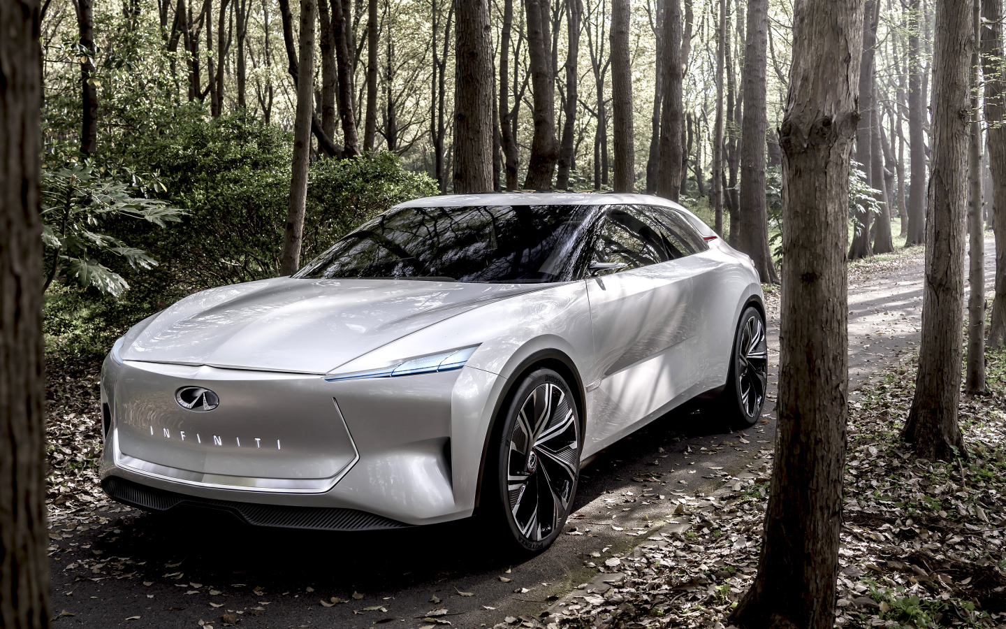 Серебристый автомобиль Infiniti Qs Inspiration 2019 года в лесу