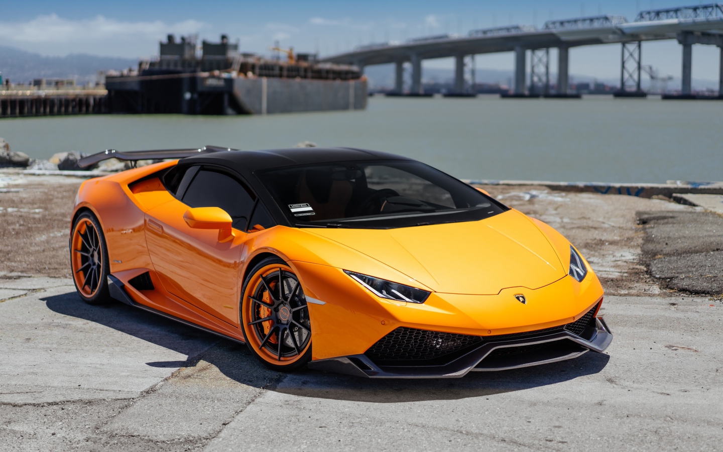 Оранжевый быстрый Lamborghini Huracan в порту у воды