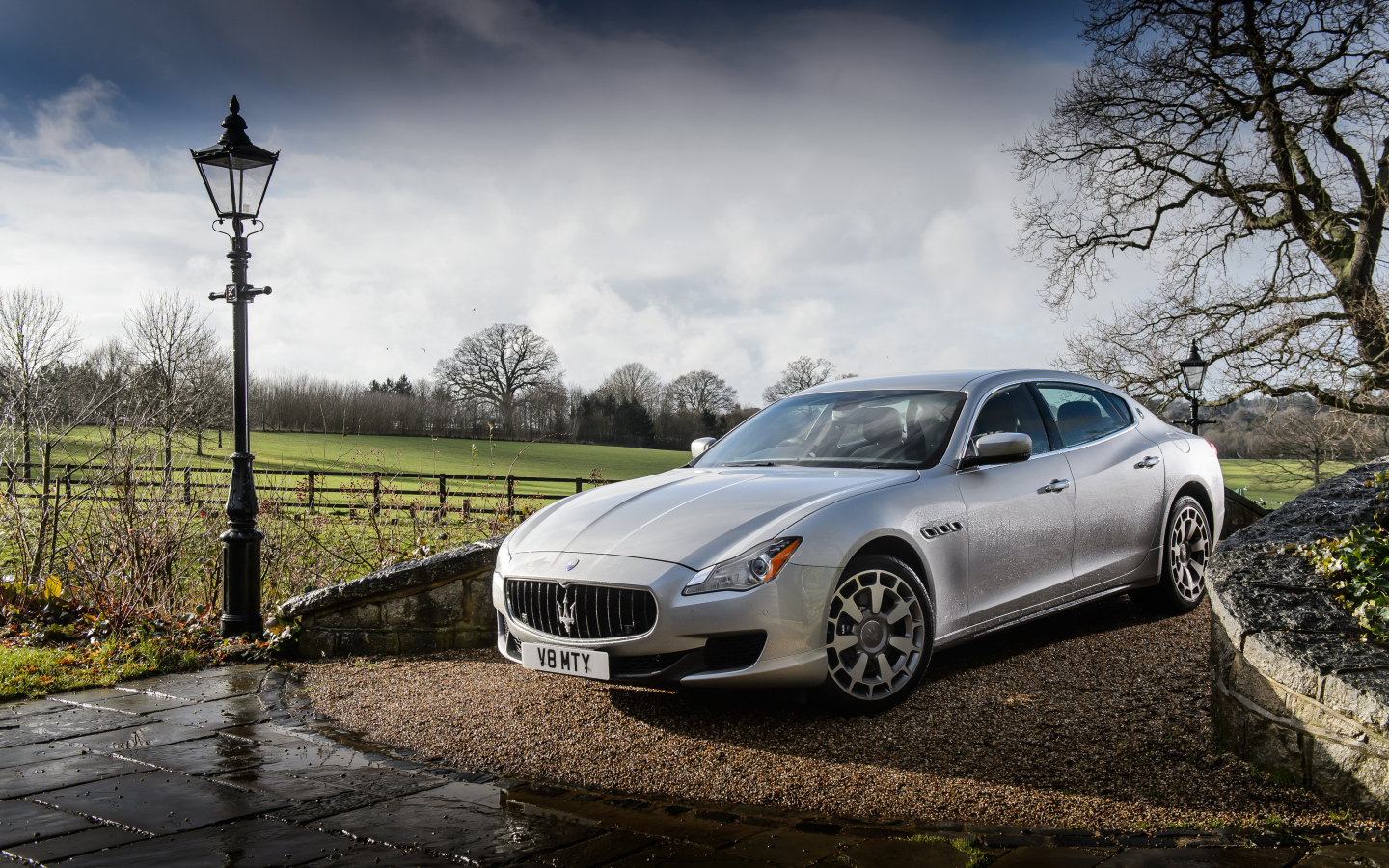 Серебристый стильный дорогой автомобиль Maserati Quattroporte на дороге после дождя
