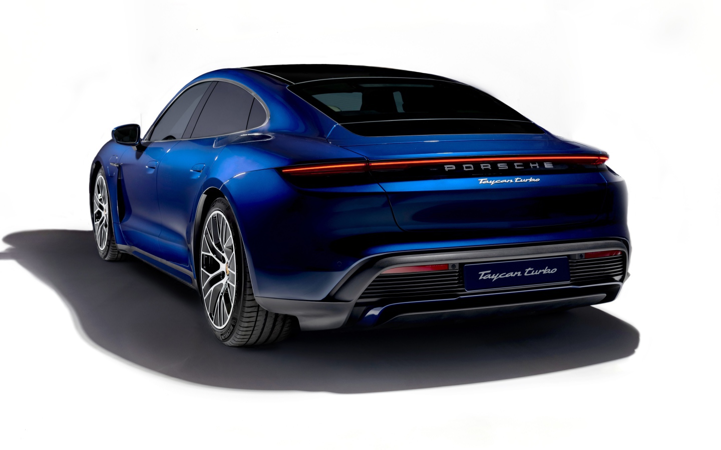 Синий автомобиль Porsche Taycan Turbo 2019 года на белом фоне