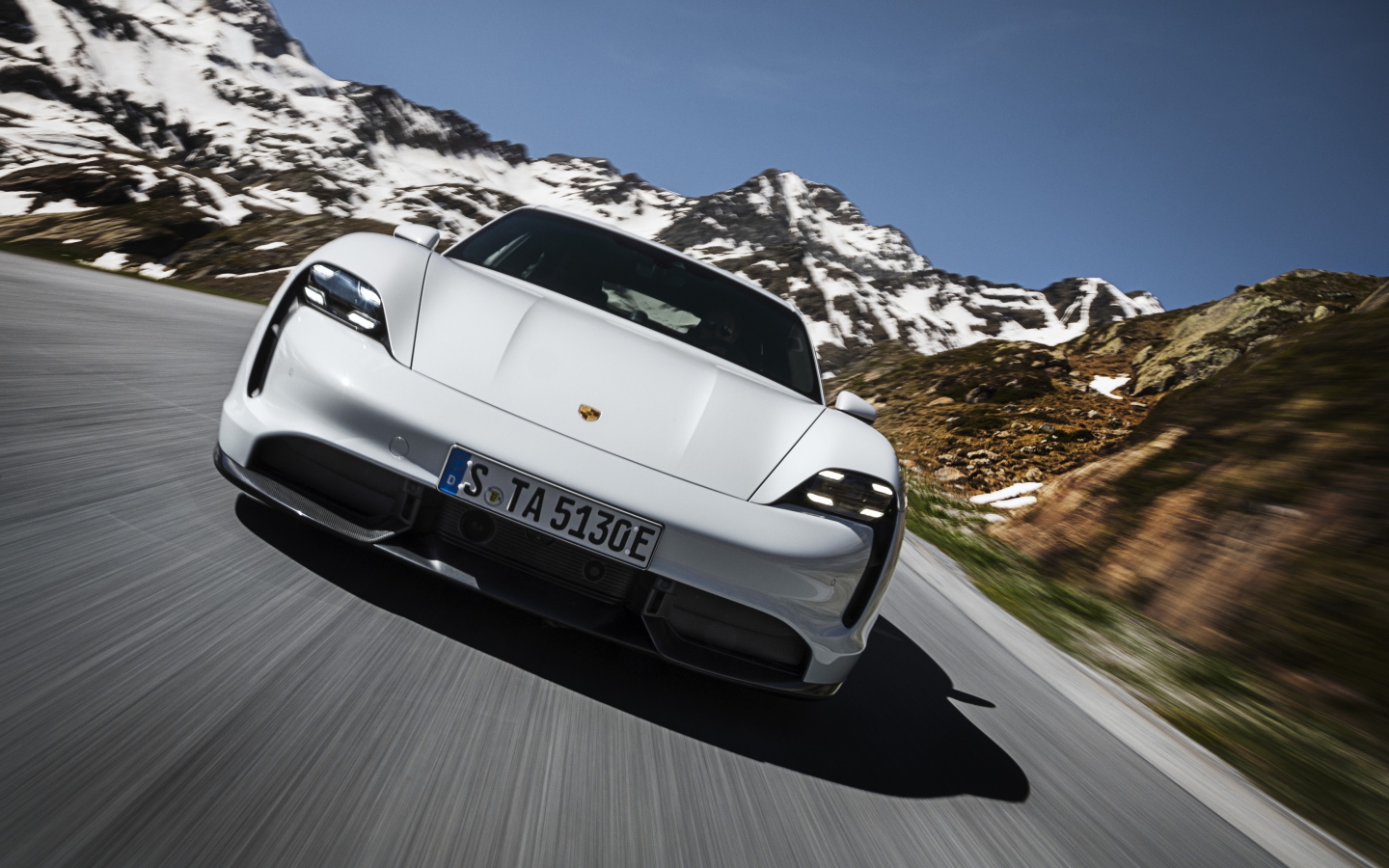 Белый автомобиль Porsche Taycan Turbo S 2019 года на фоне заснеженных гор