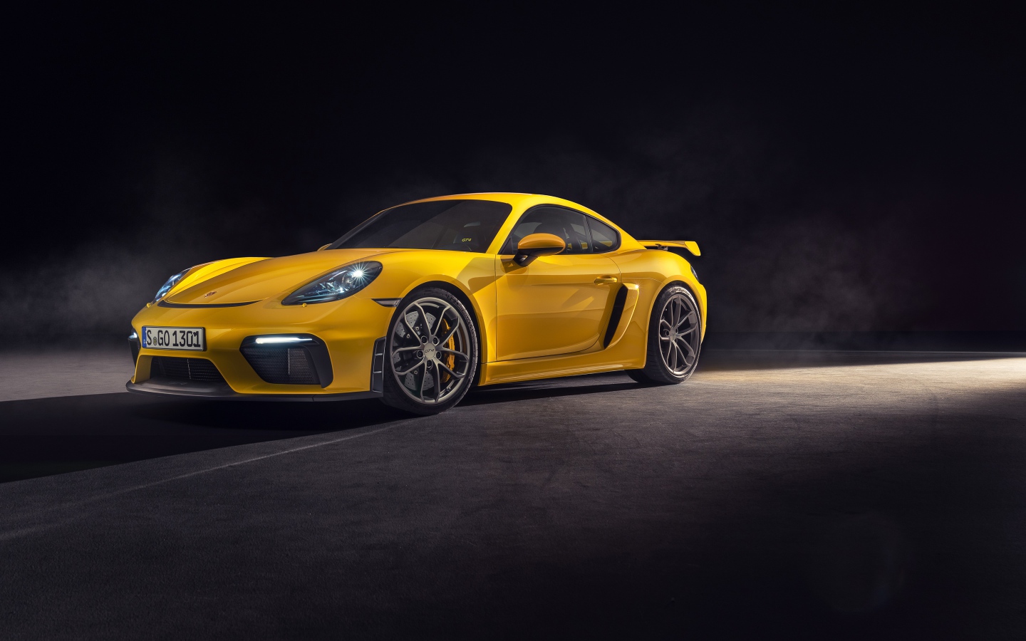 Желтый спортивный автомобиль Porsche 718 Cayman GT4, 2019 года на сером фоне