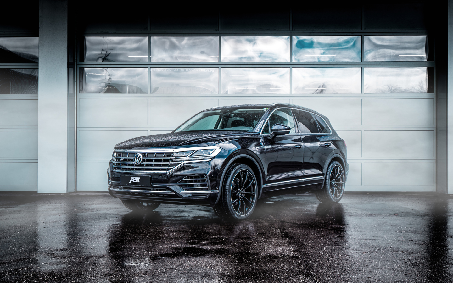 Черный автомобиль Volkswagen Touareg 2018 года у гаража