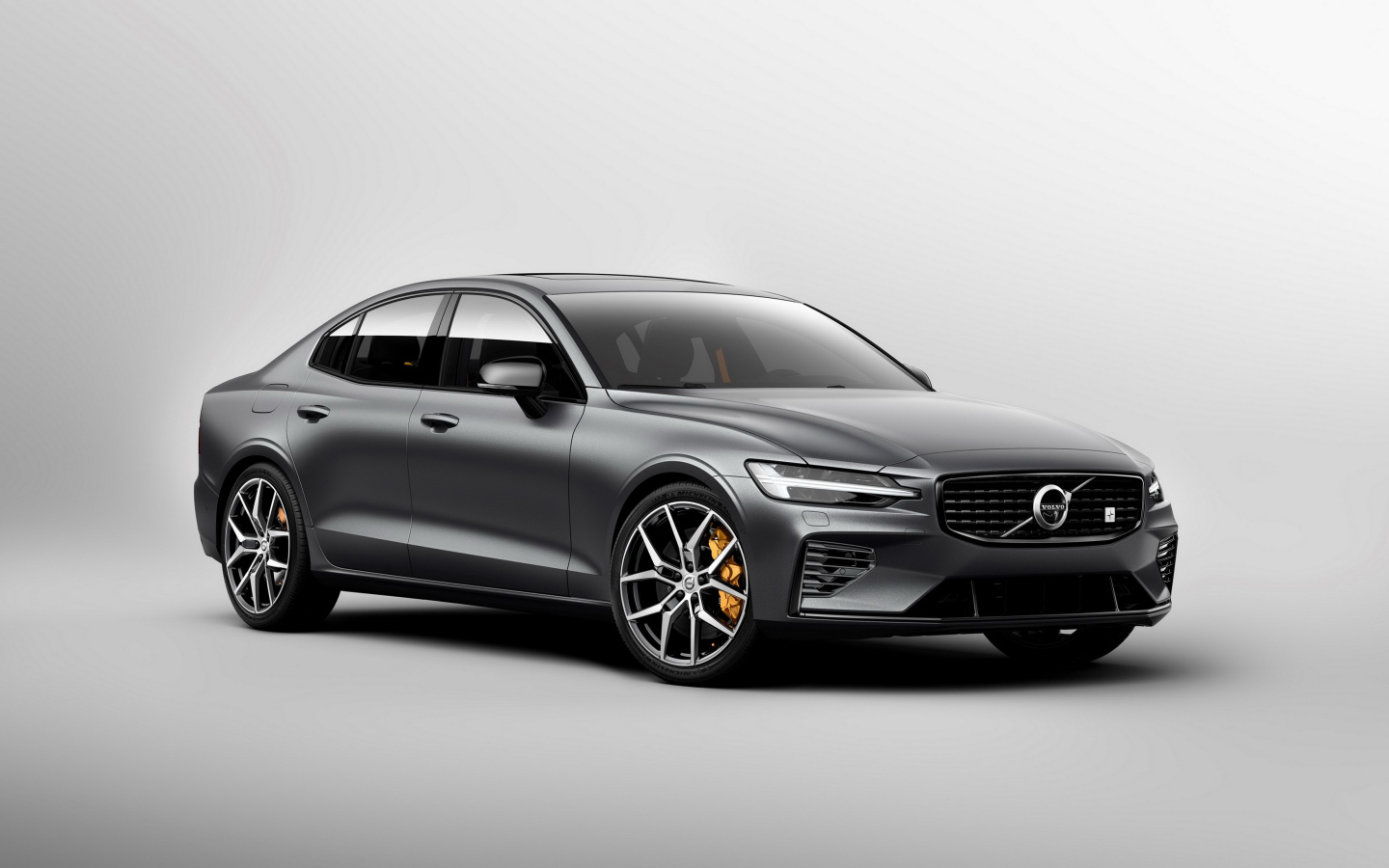 Серебристый автомобиль Volvo S60, 2018 года на сером фоне