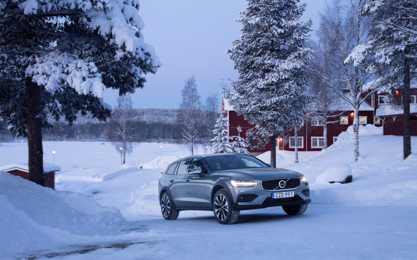 Автомобиль Volvo V60 на фоне заснеженных деревьев 