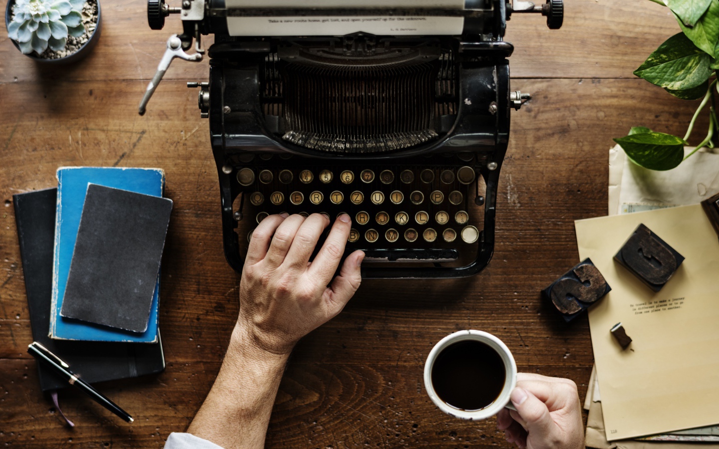 Мужчина с чашкой кофе в руке печатает на старой печатной машинке 